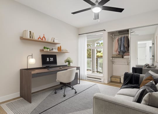 a living room with a couch and a desk and a ceiling fan