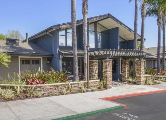 a house with a driveway and palm trees in front of it