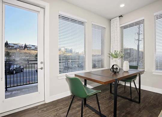 A room with a table and chairs and a view of a street outside.