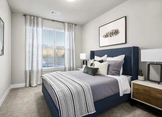 A bedroom with a large bed and a window with curtains.