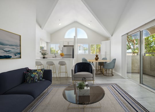 a living room with a couch and a coffee table in front of a kitchen with a breakfast