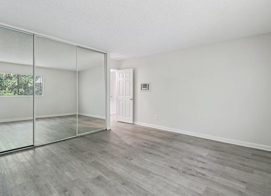 A room with a sliding glass door and wood flooring.
