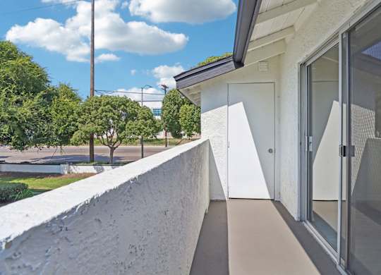 A white building with a glass door and a concrete wall.