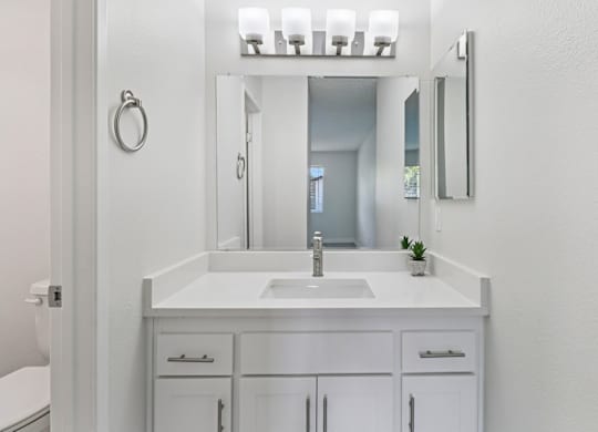 A white bathroom with a sink and mirror.