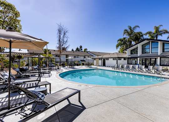 A pool area with sun loungers and a building in the background.