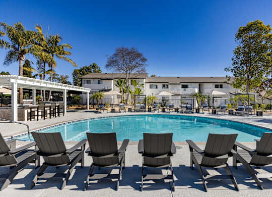 A pool surrounded by lounge chairs and palm trees.