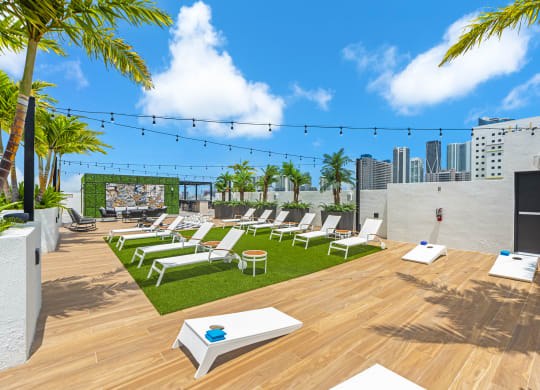 a roof top lounge area with lounge chairs and a view of the city