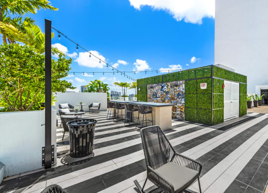 a patio with chairs and tables and a green wall with mosaics on it