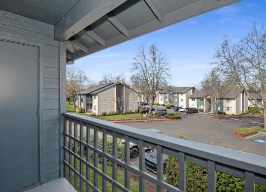 A view from a balcony overlooking a parking lot and apartment buildings.