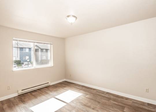 A room with a window and a radiator on the floor.