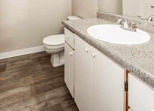 A bathroom with a toilet, sink, and mirror.