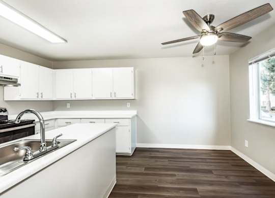 A kitchen with white cabinets and a wooden floor.