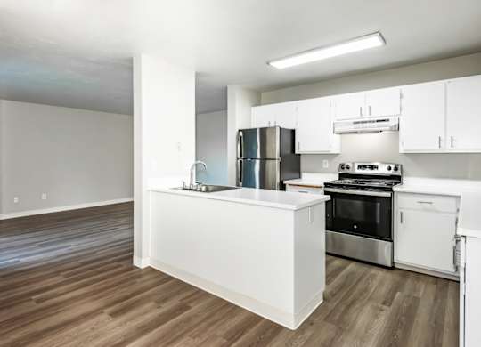 A kitchen with white cabinets and a wooden floor.