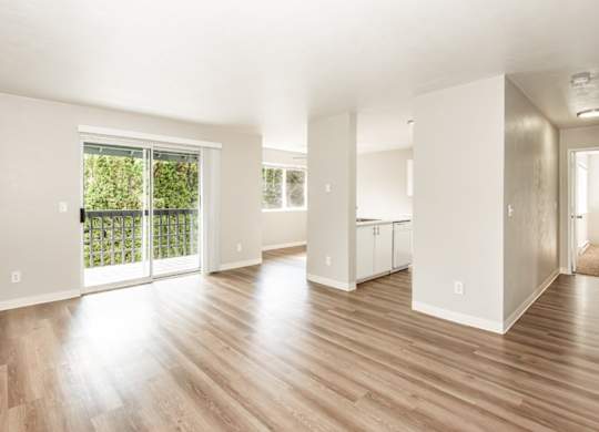 A spacious living room with wooden floors and white walls.