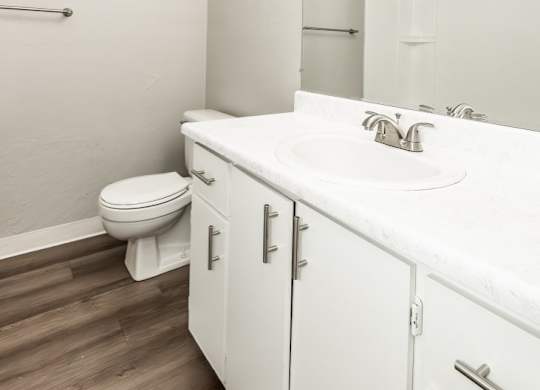 A white bathroom with a toilet, sink, and mirror.