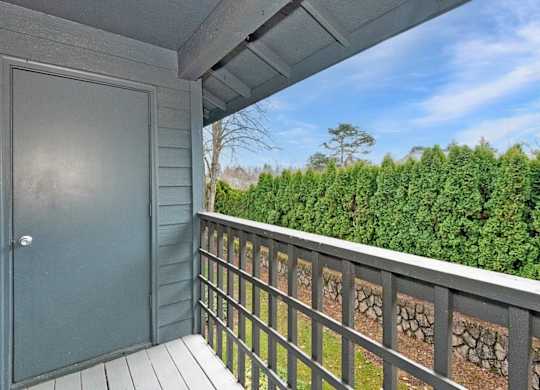 A view from a balcony with a grey door and a stone wall.