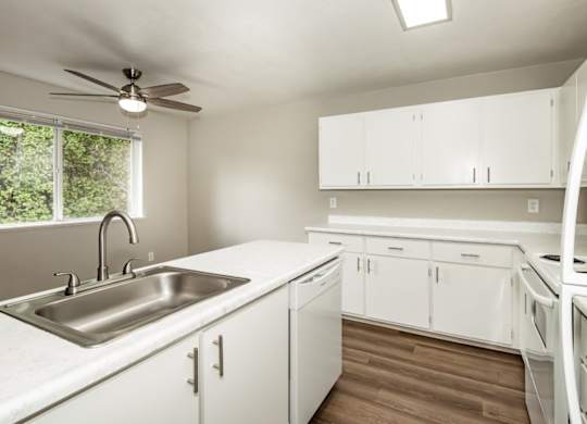 A kitchen with white cabinets and a stainless steel sink.
