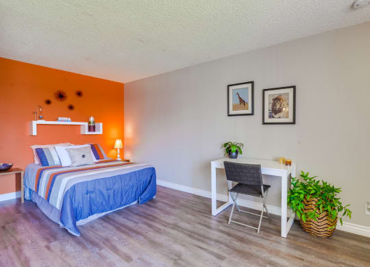 Bedroom with Stylish Decor, Plank Flooring, Beige and Orange Walls, Small Shelf, and Popcorn Ceiling at Las Brisas Apartments, Colton, CA, 92324