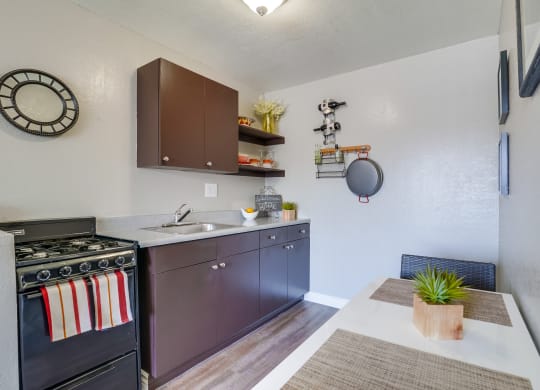 Kitchen with Stainless Appliances, White Cabinets, Plank Flooring, and Granite Countertops at Las Brisas Apartments, California