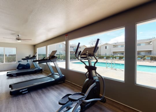 Fitness Center with Treadmills, Exercise Bike, and View of the Pool at Aspire High Desert Apartments, Victorville, 92392