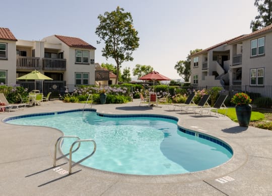 our apartments have a large pool with chairs and umbrellas at Aspire Corona, Corona, California