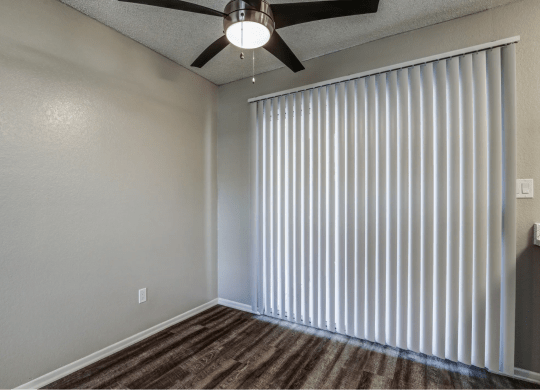 an empty living room with window blinds and a ceiling fan at Aspire Seneca, Victorville