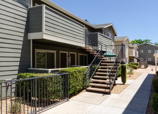 an exterior view of a gray house with stairs and a sidewalk at Aspire High Desert Apartments, Victorville, CA, 92392