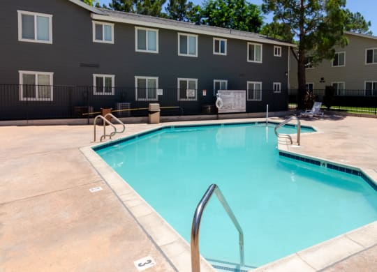 our apartments have a swimming pool with a fence and a building in the background at Aspire High Desert Apartments, Victorville, CA
