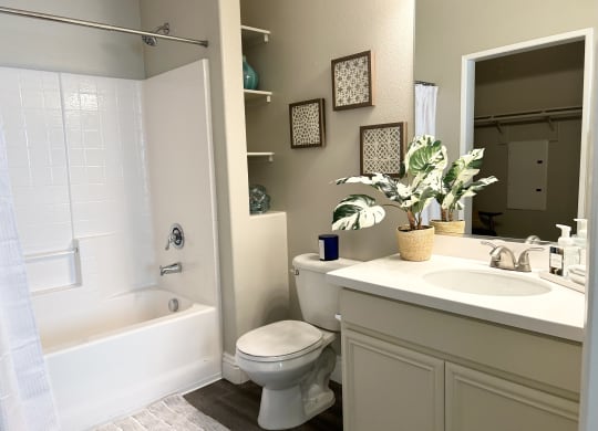 a bathroom with a white toilet next to a white bathtub at Riverton of the High Desert Apartments, Victorville