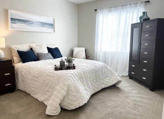 a bedroom with a large bed and a dresser at Riverton of the High Desert Apartments, California, 92392