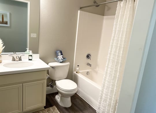a bathroom with a bathtub toilet and sink at Riverton of the High Desert Apartments, Victorville, CA