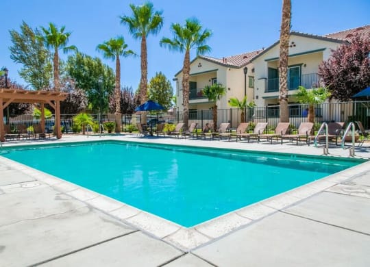 Gated Pool Surrounded by Lounge Seating at Riverton of the High Desert Apartments, Victorville