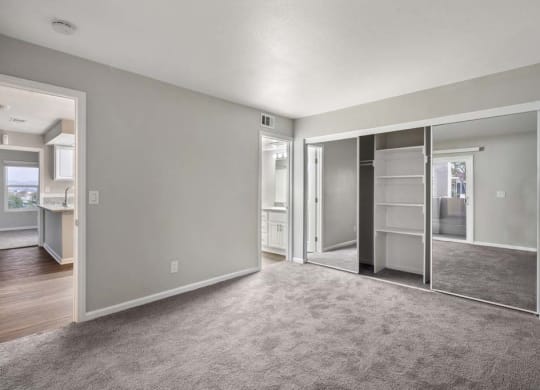 a bedroom with a closet and a kitchen in the background at Aspire Corona, California