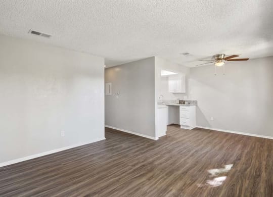 a living room with a ceiling fan and a kitchen in the background at Aspire Redlands, California