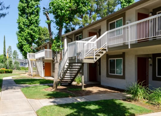 an exterior view of a building with stairs and grass and trees at Aspire Redlands Apartments, Redlands, 92374