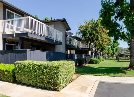 an apartment building with a lawn and trees in front of it at Aspire Redlands Apartments, Redlands, CA