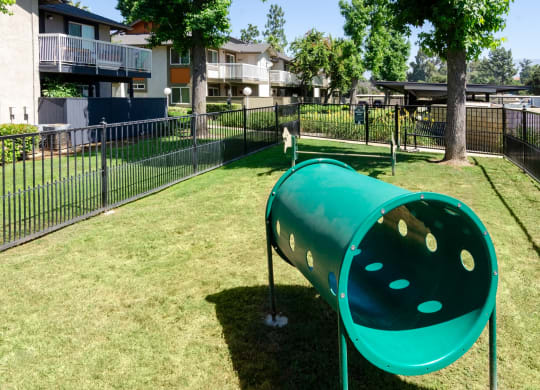 a green seesaw in a park next to a fence at Aspire Redlands Apartments, Redlands, 92374