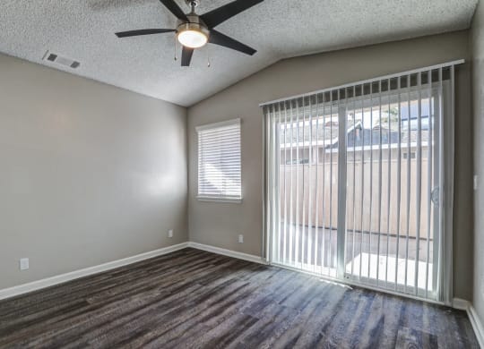 an empty living room with a large window and a ceiling fanat Aspire Seneca, Victorville