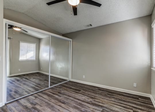 an empty living room with a ceiling fan and a mirrored closetat Aspire Seneca, Victorville