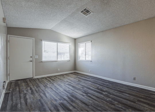 the living room of an empty home with wood flooring and a door and windowat Aspire Seneca at Aspire Seneca, Victorville, California