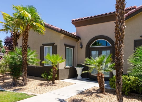 a house with palm trees in front of it at Riverton of the High Desert Apartments, Victorville, CA