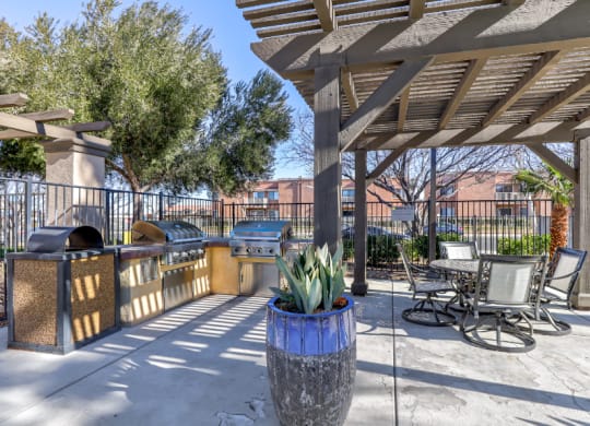 a patio with a pergola and tables and chairs at Riverton of the High Desert Apartments, California, 92392