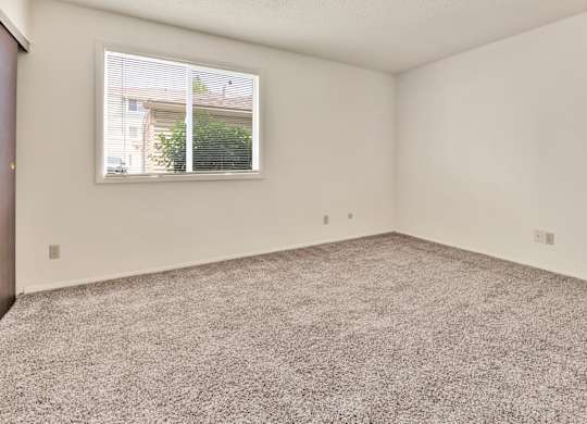 A room with a carpeted floor and a window. at Winding Hills Apartments, Iowa
