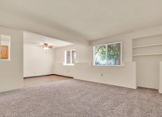 A spacious room with a ceiling fan and two windows. at Winding Hills Apartments, Iowa