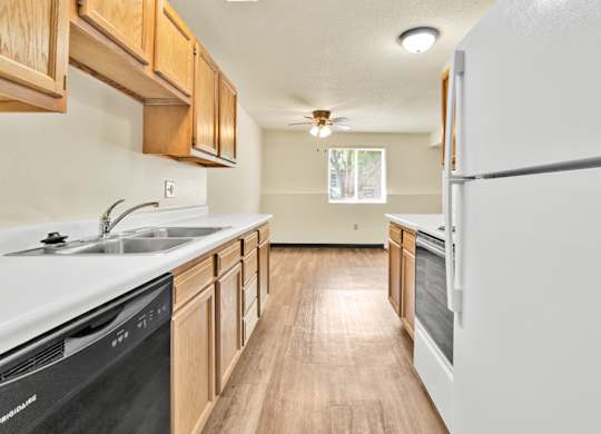A kitchen with wooden cabinets and a black dishwasher. at Winding Hills Apartments, Davenport  52807