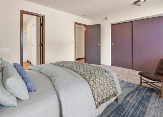 A bedroom with a large bed and a chair. at Winding Hills Apartments, Davenport  52807