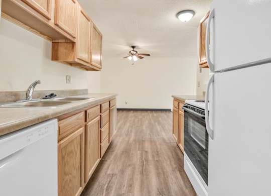 A kitchen with wooden cabinets and a white refrigerator. at Winding Hills Apartments, Davenport , Iowa