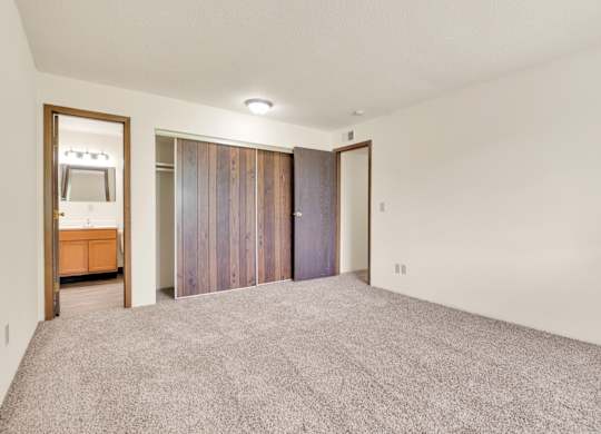 A room with a grey carpet and a wooden cabinet. at Winding Hills Apartments, Davenport , IA