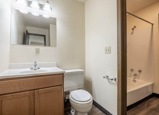 A bathroom with a toilet, sink, and mirror. at Winding Hills Apartments, Davenport , Iowa