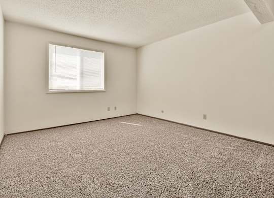 A room with a carpeted floor and a window. at Winding Hills Apartments, Davenport , IA